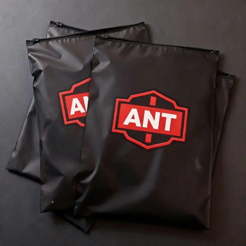 Fan arrangement of black PVC zipper bags with red custom logo on dark background.