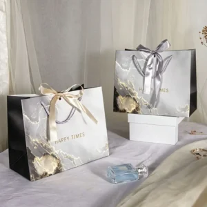 Black and grey marble luxury jewelry packaging paper bag with gold foil accents and silver ribbon bow.