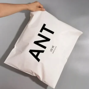Hand holding a custom white compostable poly mailer bag printed with black ANT logo