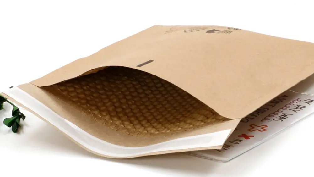 Angled close-up of open compostable padded envelope revealing interior shockproof cushioning matrix