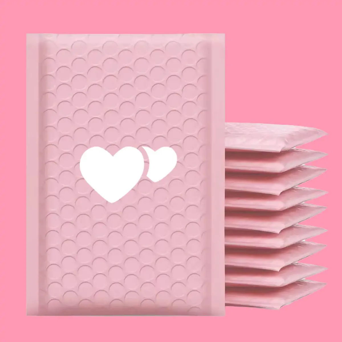 Bulk stack of custom pink recycled padded bubble mailers with embossed heart pattern