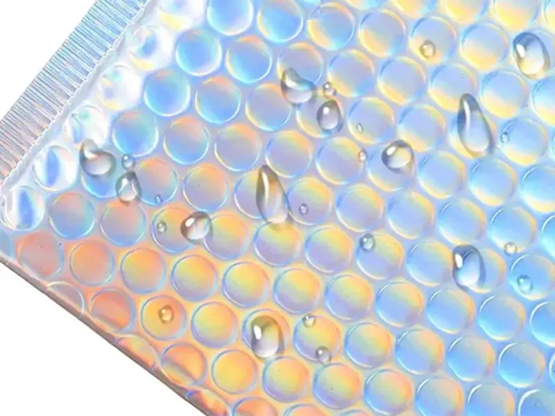 Water droplets beaded on metallic holographic bubble mailer demonstrating waterproof outer PET film