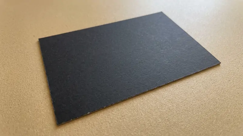 Macro edge and surface view of 380gsm pigment-dyed black cardstock with solid black core